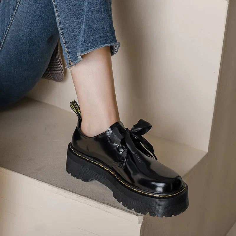 Black women's thick soled lace-up shoes with ribbon and cross strap detail on a superfine fibre upper.