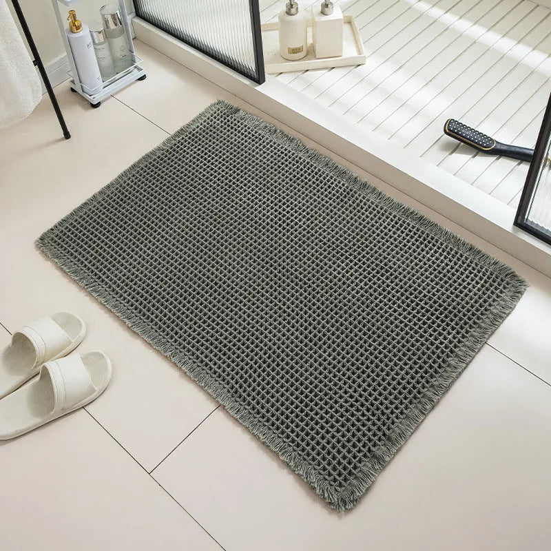 Checkered patterned non-slip absorbent bathroom floor mat in a neutral colour on tiles.