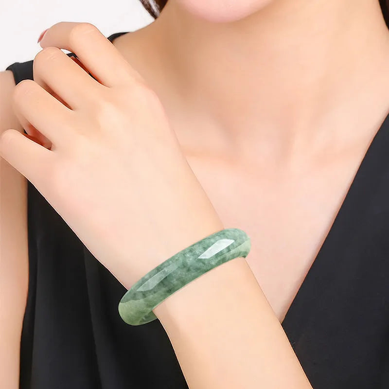 Natural emerald green jade bracelet on wrist, showing simple band style and deep pea green stone colour.