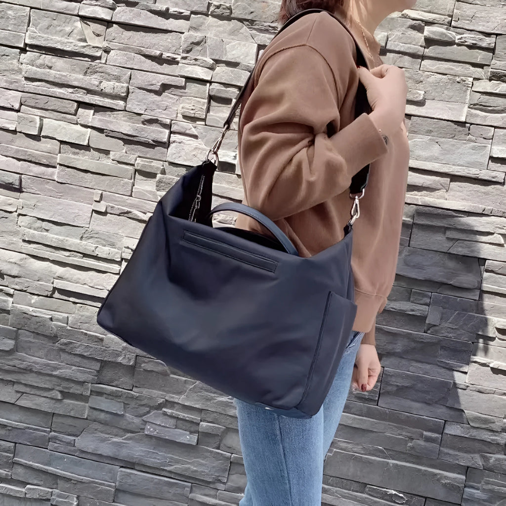 Nylon waterproof shoulder bag in black or light khaki measuring 35cm wide with leather accents