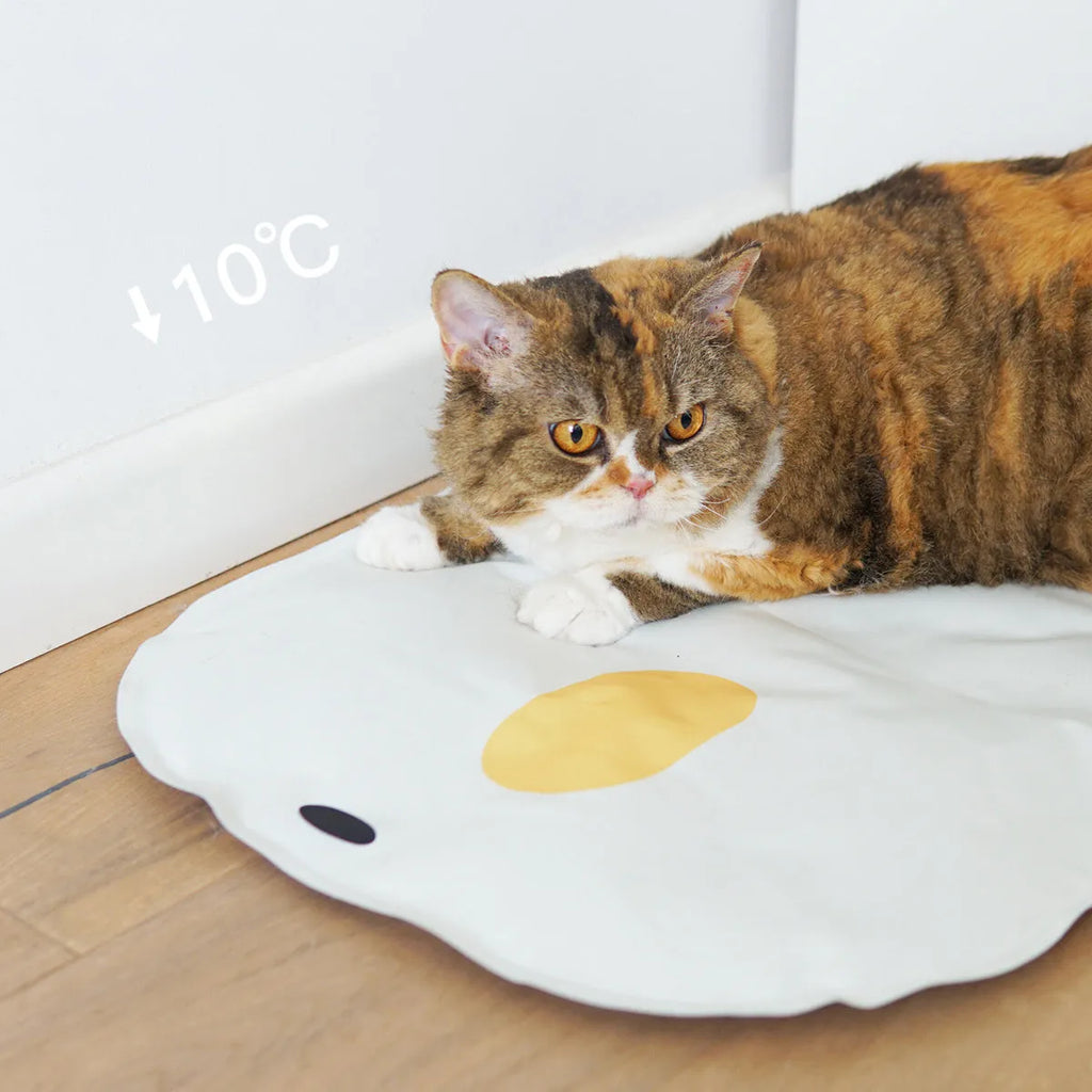 Yellow chick-shaped pet cooling mat on a wooden floor, showing non-stick fabric surface.
