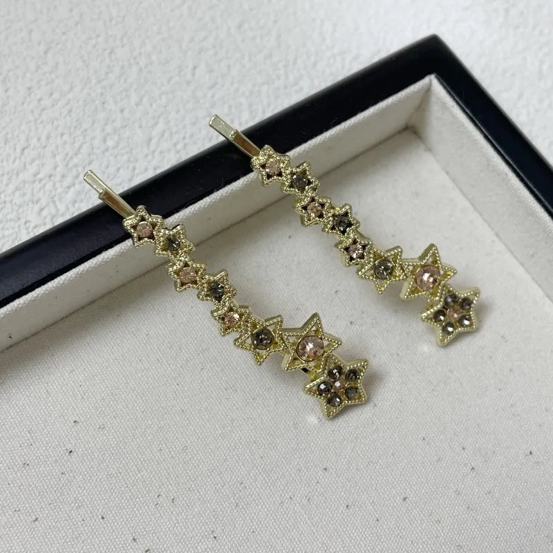 Gold electroplated rhinestone barrettes with side clip design featuring star and letter charms