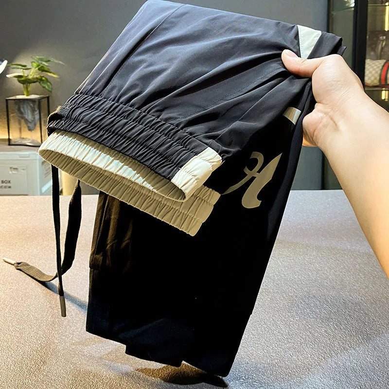 Men's black ice silk cropped ankle banded trousers on hanger showing thin fabric and banded ankle detail