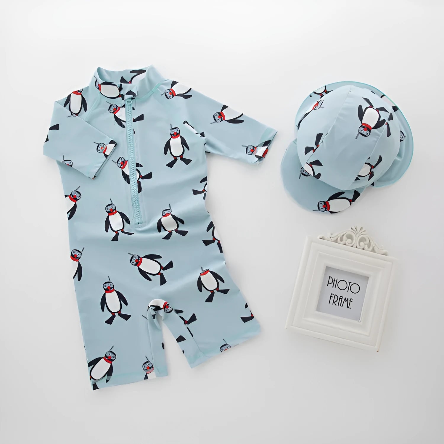 Boys' long sleeve penguin print swimsuit and matching swim cap set on a white background.