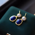 A pair of sterling silver earrings with deep blue lapis lazuli pearls and simple auspicious patterns.