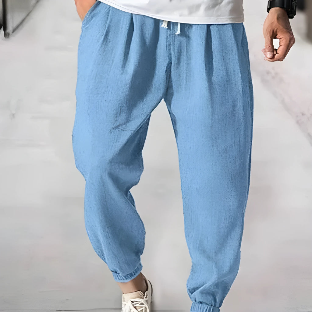 Man wearing light-coloured cotton banded ankle pants with a loose, casual fit.