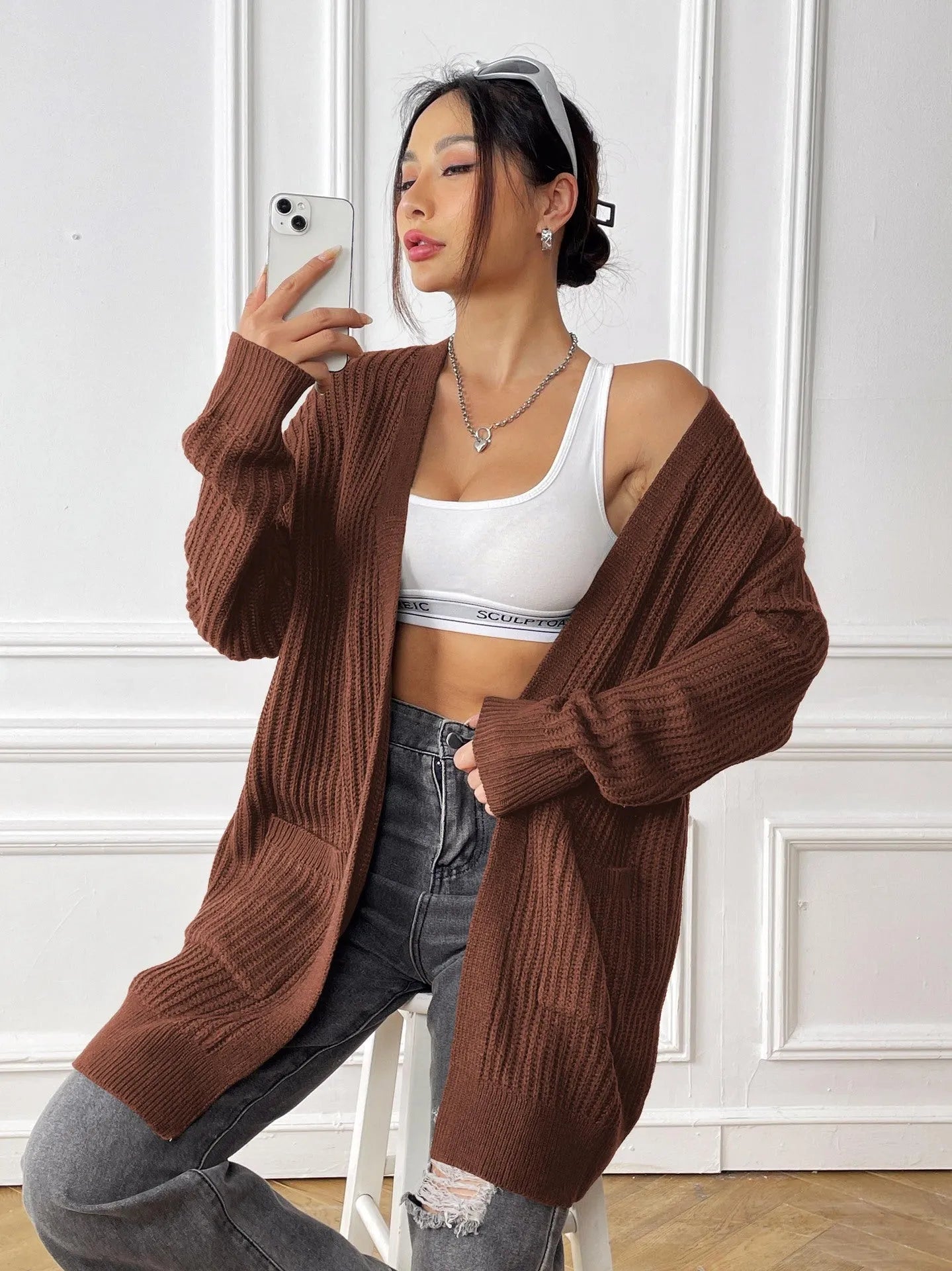 A loose-fitting, mid-length acrylic cardigan sweater in a solid colour, shown in a street hipster style.