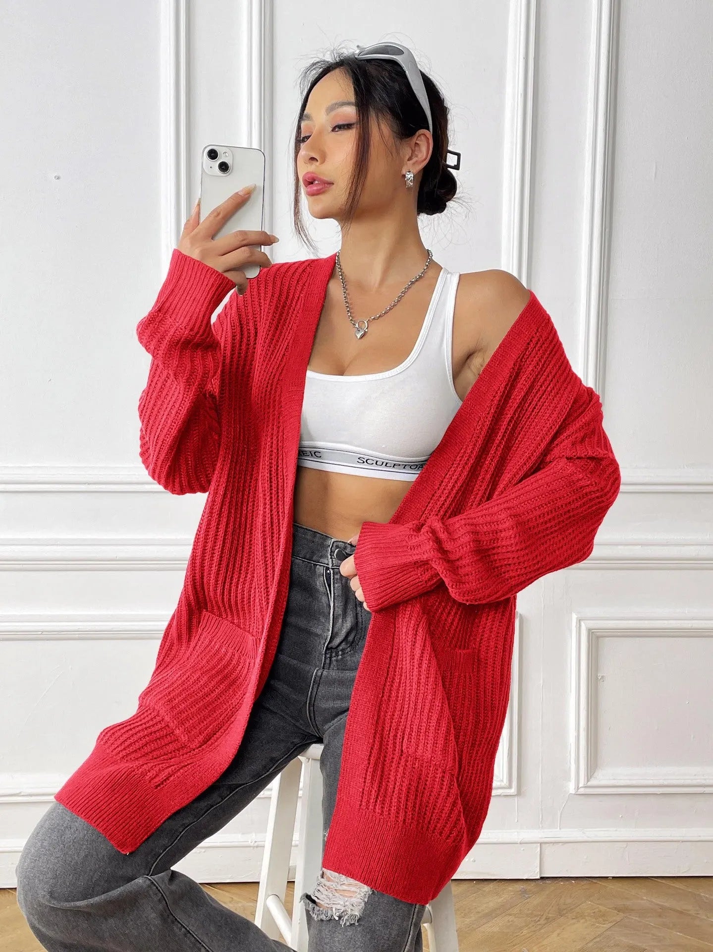 A loose-fitting, mid-length acrylic cardigan sweater in a solid colour, shown in a street hipster style.