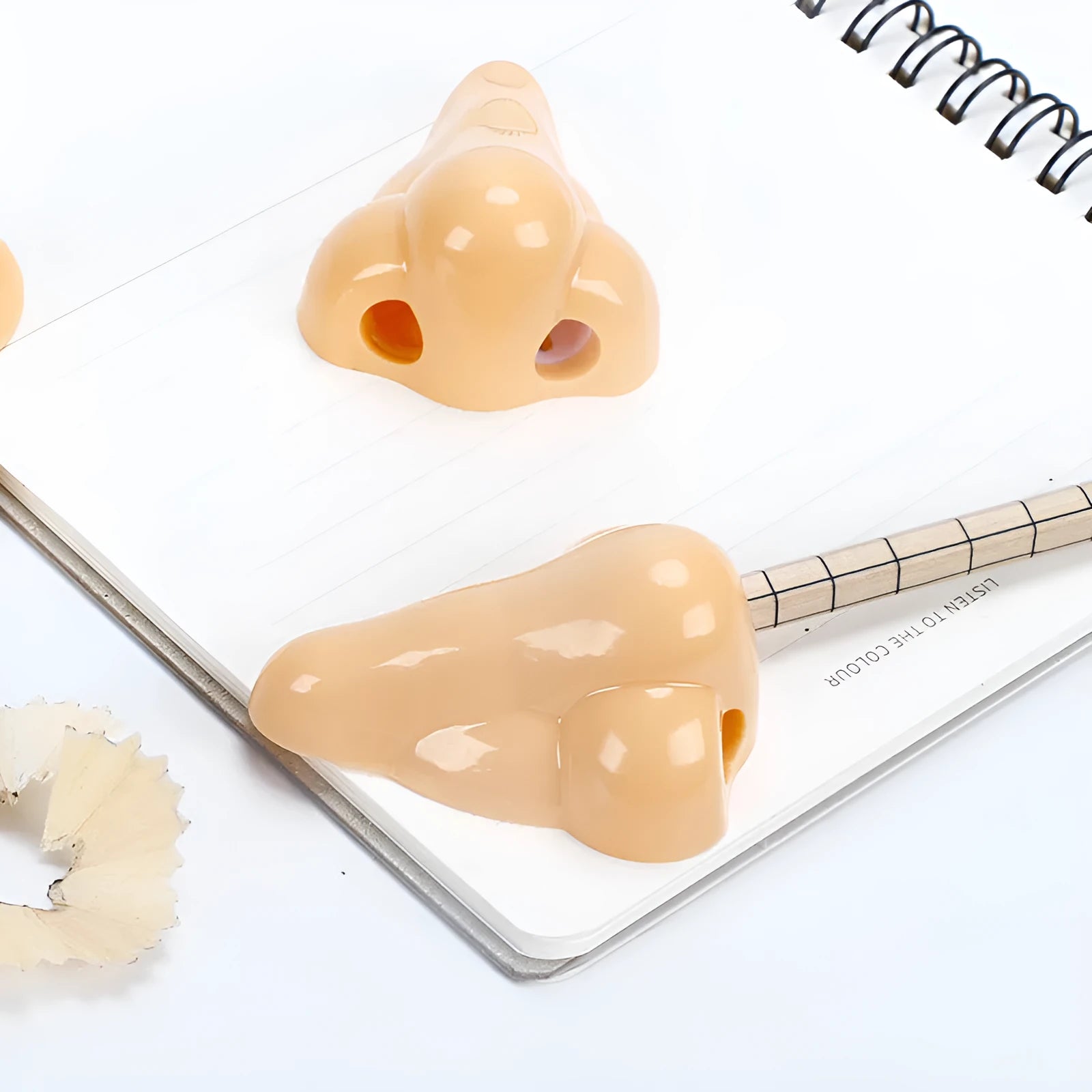 Flesh-coloured plastic geometry-shaped pencil sharpener with a large nostril.