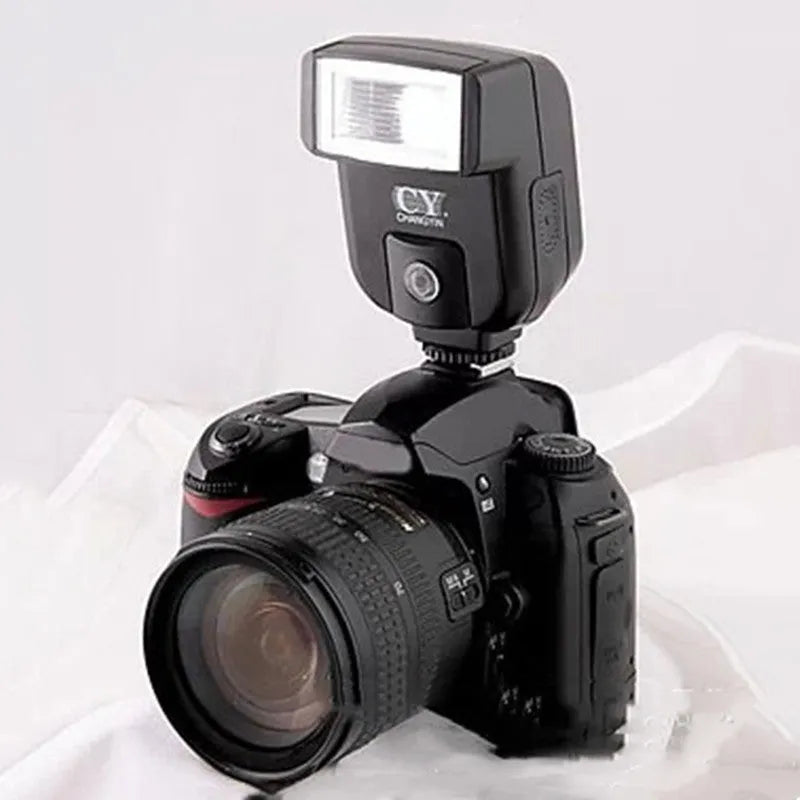 A compact black hot shoe flashgun for DSLR cameras, shown tilted upwards on its mount.