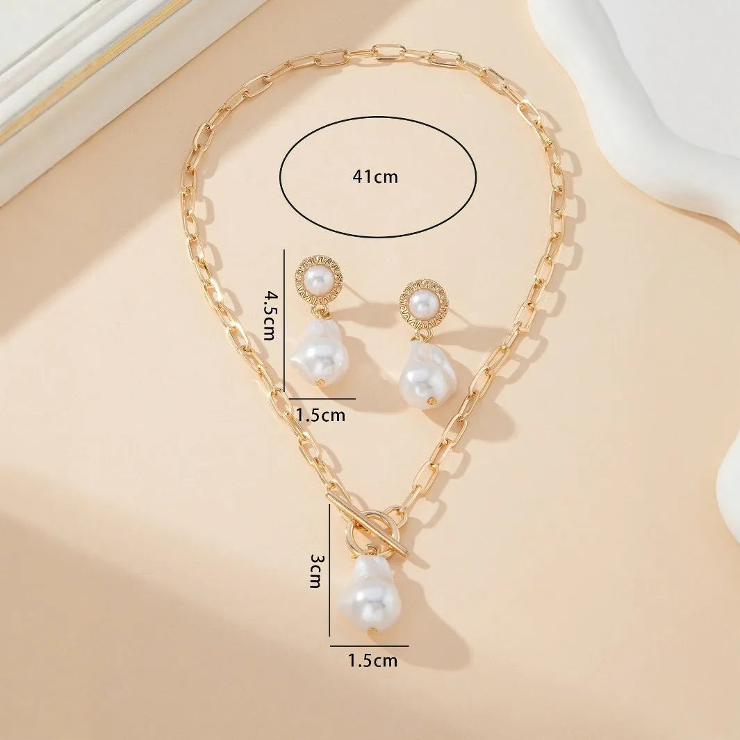 Gold-colour iron necklace and earring set with a baroque pearl pendant on a woman.
