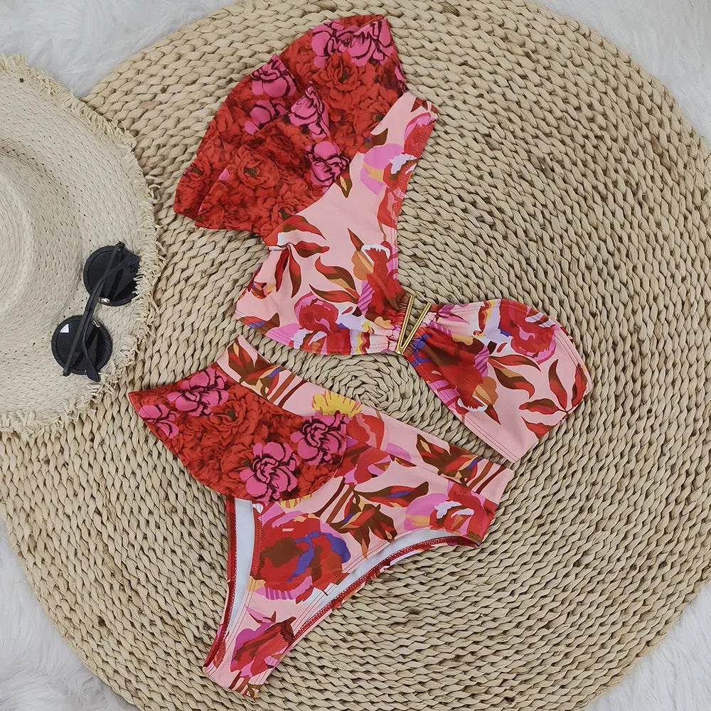 Pink one-shoulder ruffled swimsuit with red floral print and high-waist bikini bottoms