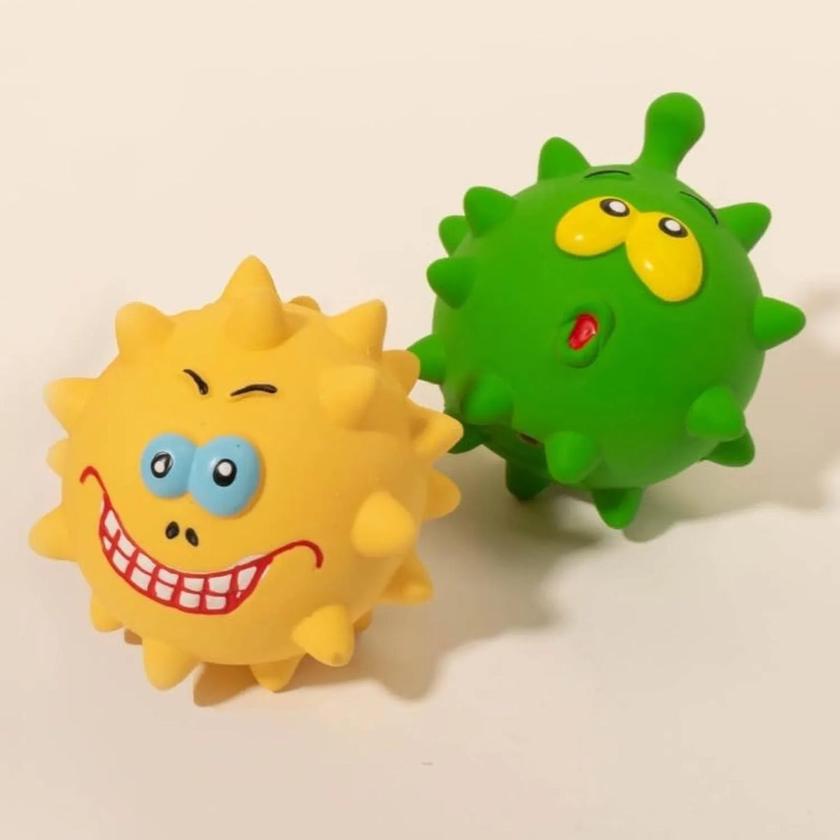 Set of four coloured latex squeaky dog balls with cute face designs on blue green red yellow backgrounds