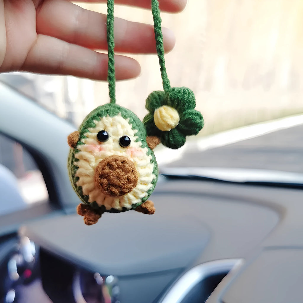 Handmade crocheted avocado-shaped car pendant in wool, shown in three colour variations.