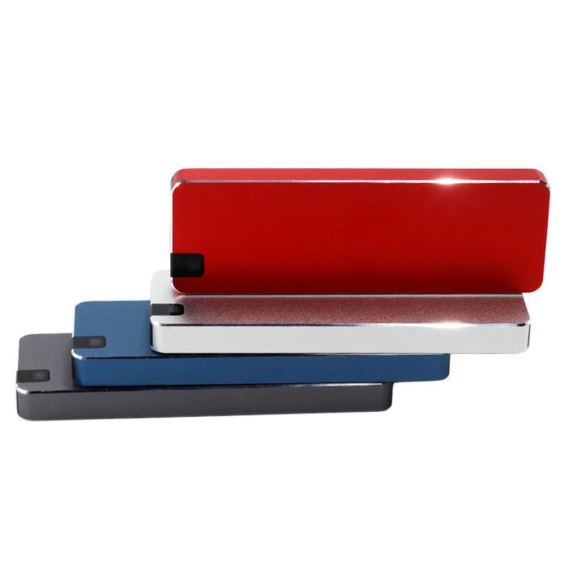 White portable external SSD with metal shell and USB cable next to a laptop.