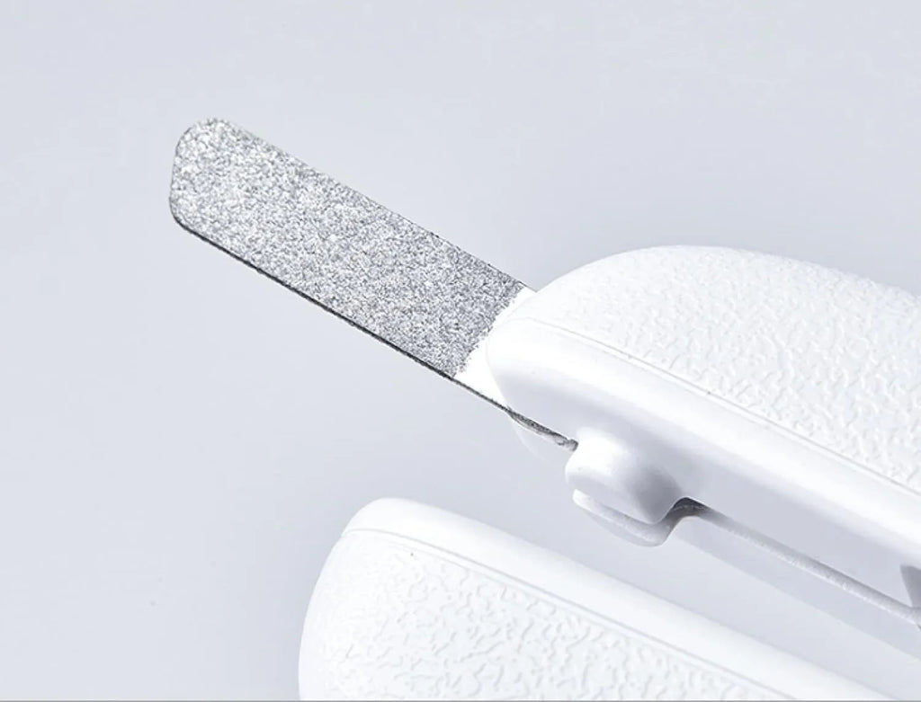 White pet nail clippers with LED light, transparent guard, and a nail file on a table