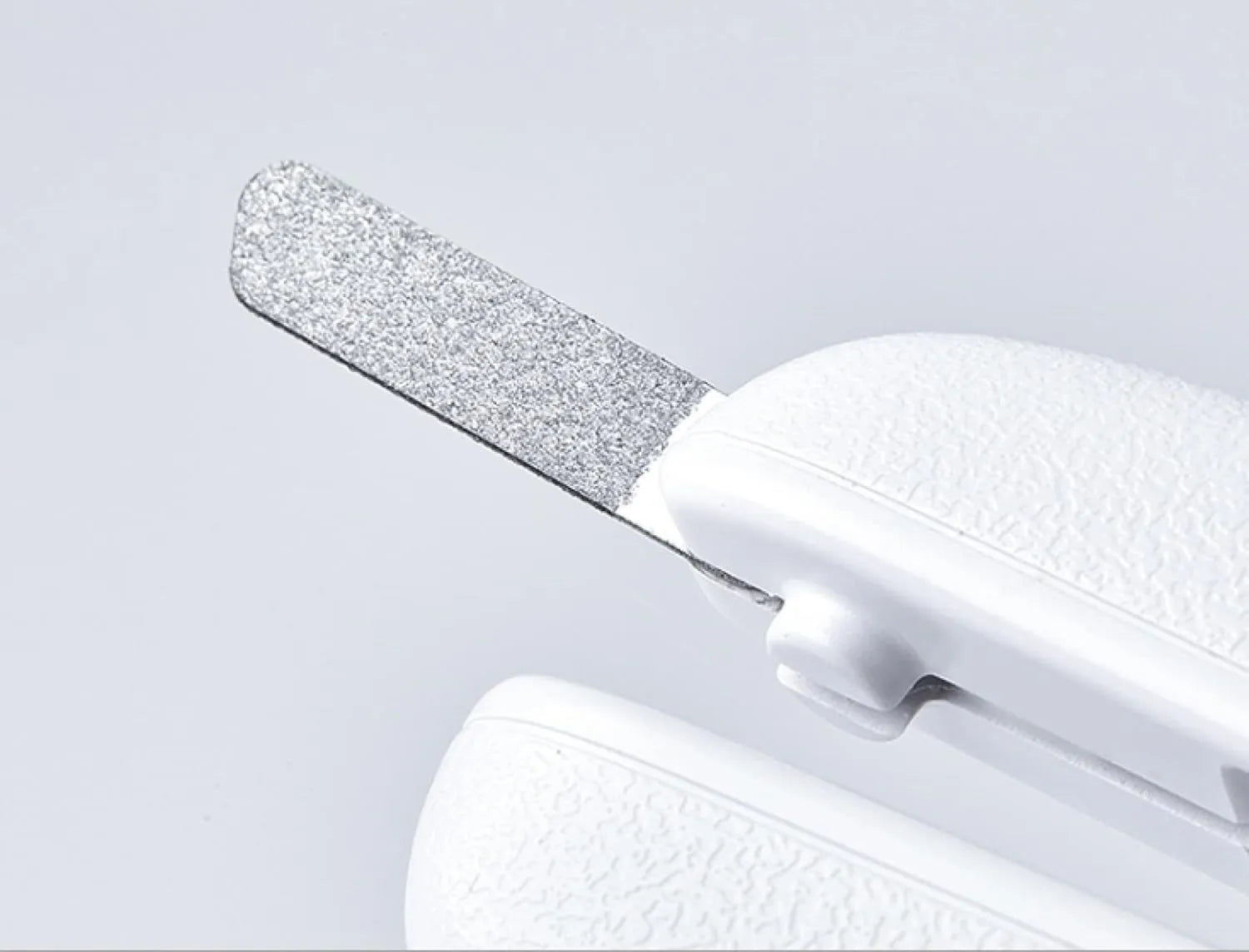 White pet nail clippers with LED light, transparent guard, and a nail file on a table