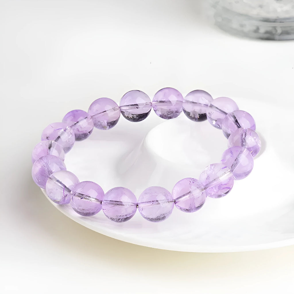 Lavender round amethyst bead bracelet with geometric water ripple design on a wrist.