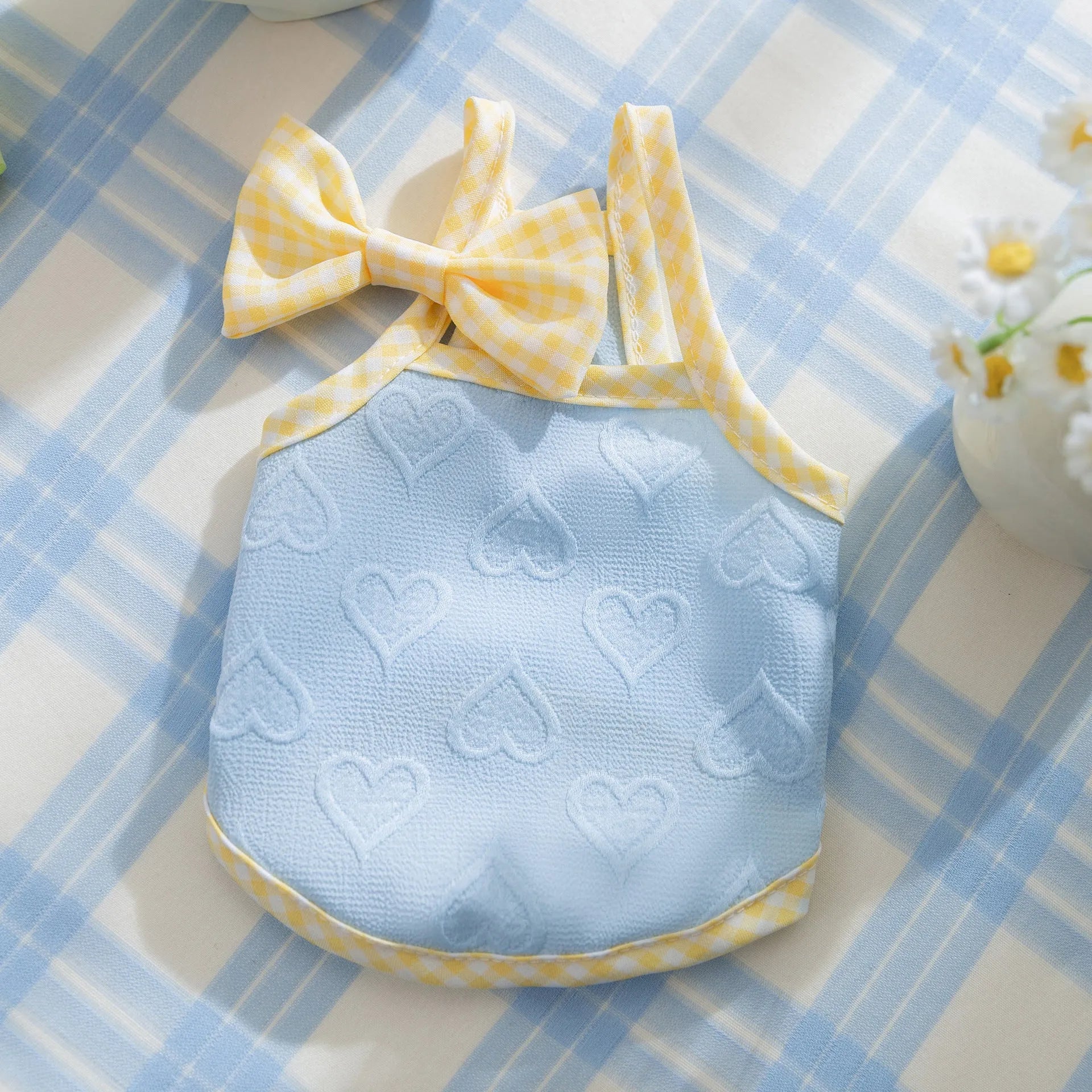 Small dog wearing a blue elastic vest with a white heart and bow suspenders decoration.