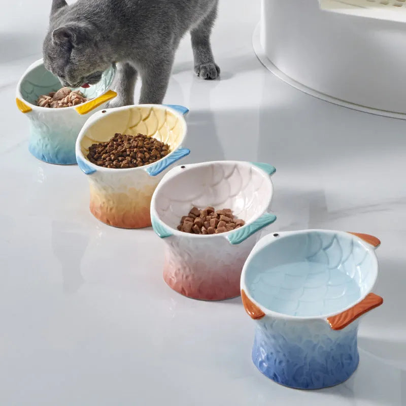 Blue ceramic cat food bowl in a fish shape with a tilted, elevated design and non-slip base.