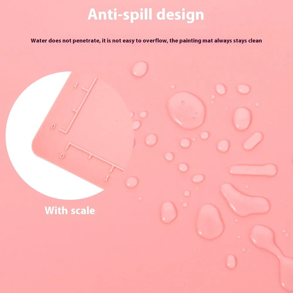 Light blue silicone painting mat with two round mixing bowls, placed on a wooden table with paintbrushes.