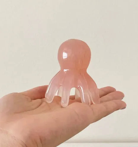 Pink octopus-shaped massage comb for periocular meridian acupressure with curved arms and storage bag