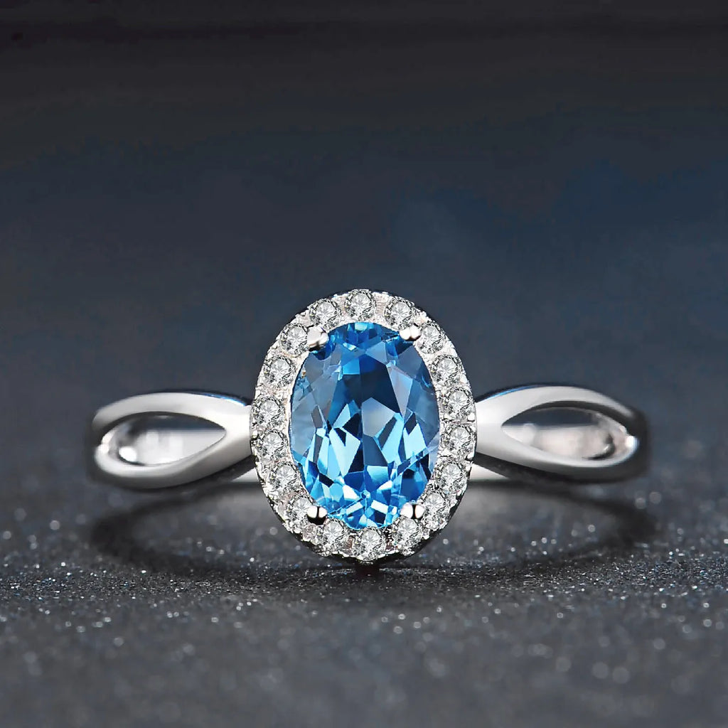 Women's sterling silver jewellery set with blue topaz stones, showing geometric earrings, necklace, ring, and pendant.