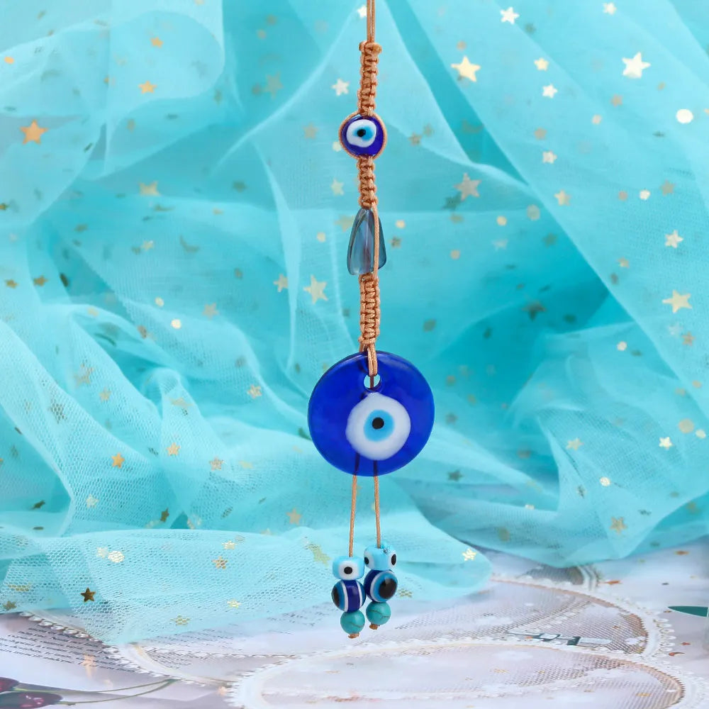 Glass evil eye bead ornament with Turkish blue eye pattern and braided string for wall or car hanging
