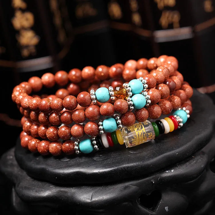 Golden star stone nugget bracelet with mantra beads and a retro fu charm on a wrist.
