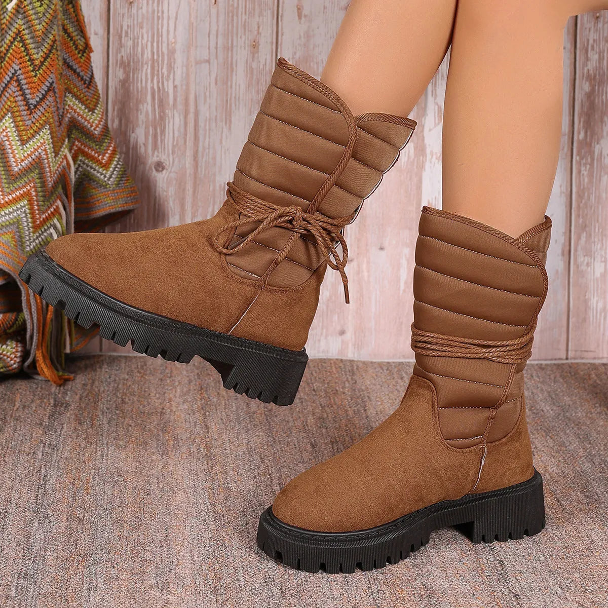Women's black chunky heel snow boots with suede upper and lace-up design on a white background.