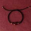 Heart-shaped cinnabar pendant on adjustable safety buckle bracelet with red cord