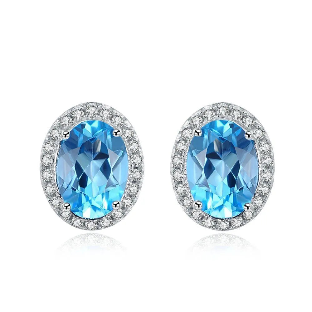 Women's sterling silver jewellery set with blue topaz stones, showing geometric earrings, necklace, ring, and pendant.