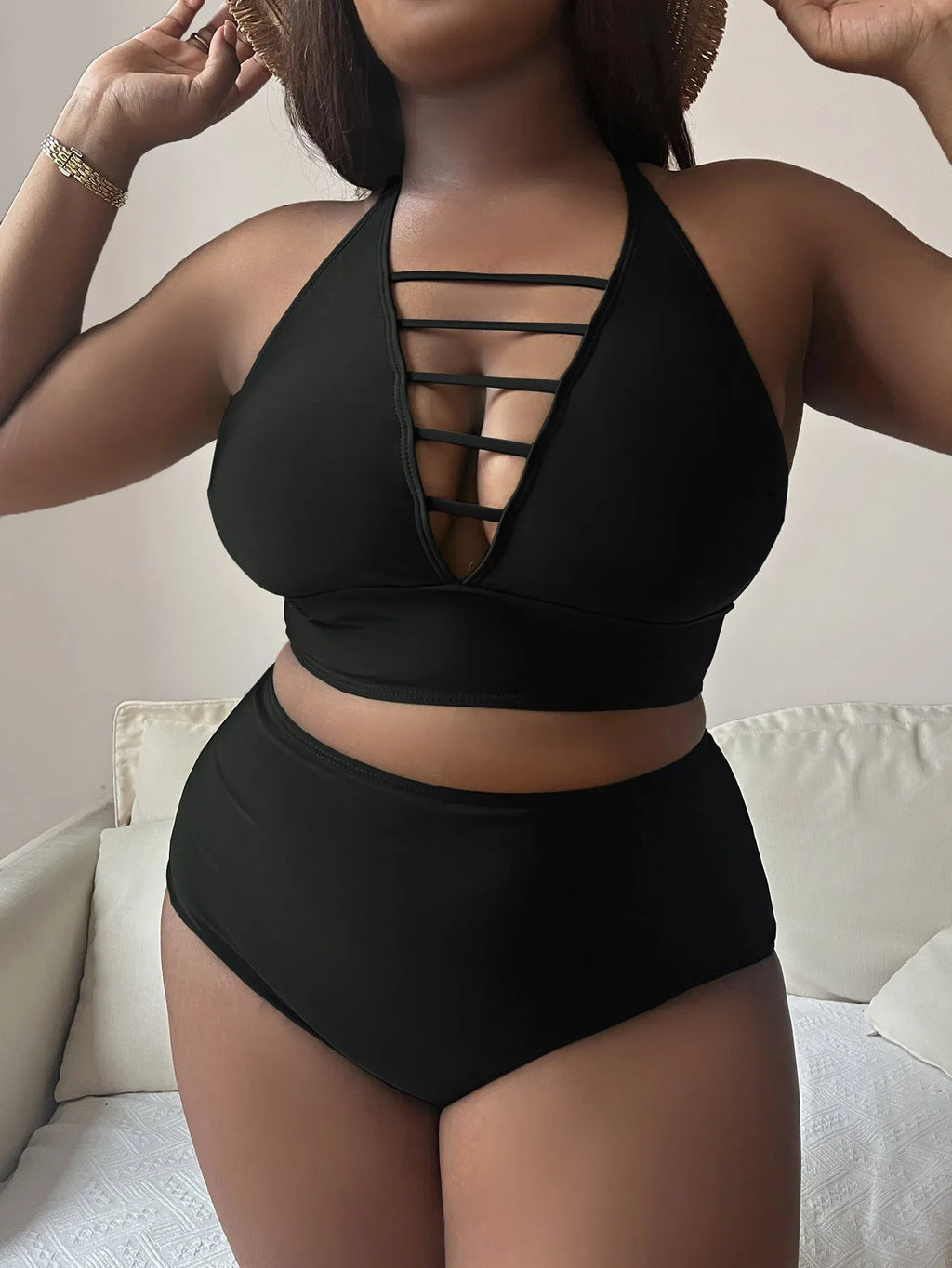 Plus size woman modelling a black halter neck bikini with cross-back straps and high-waisted briefs.