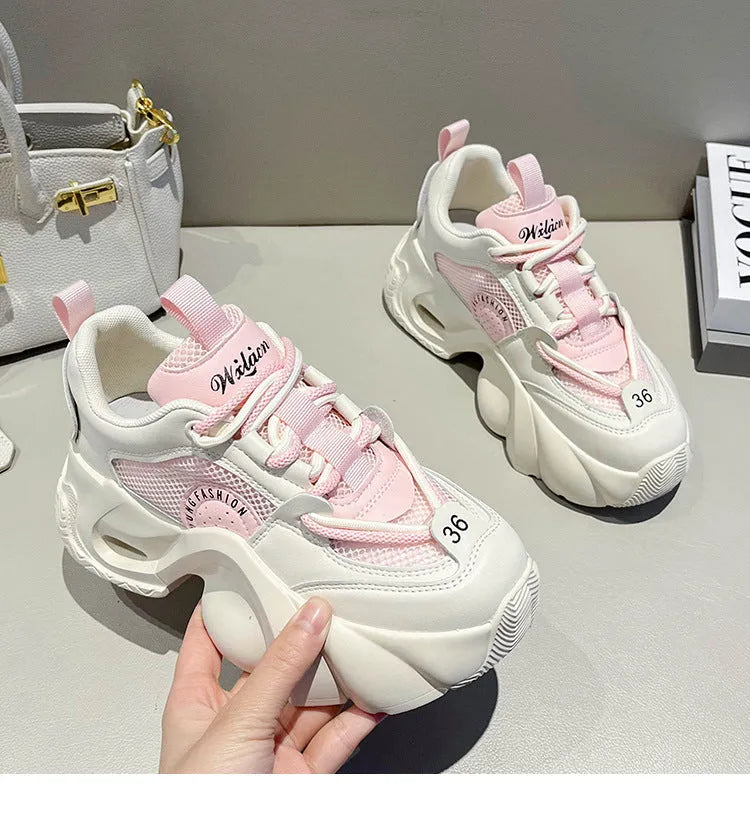 Women's pink sneakers with cross shoulder straps, thick sole, and mesh lining on a white background.