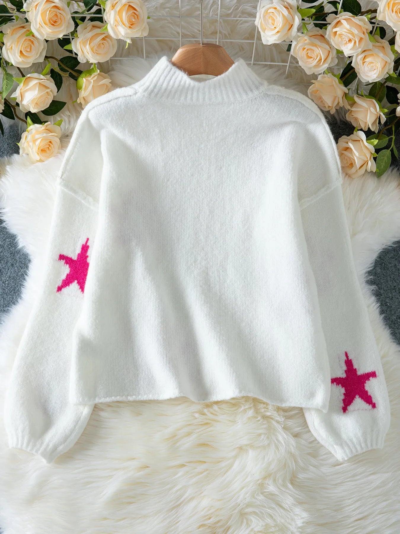 White women's loose turtleneck sweater with a large black five-pointed star pattern on the front.