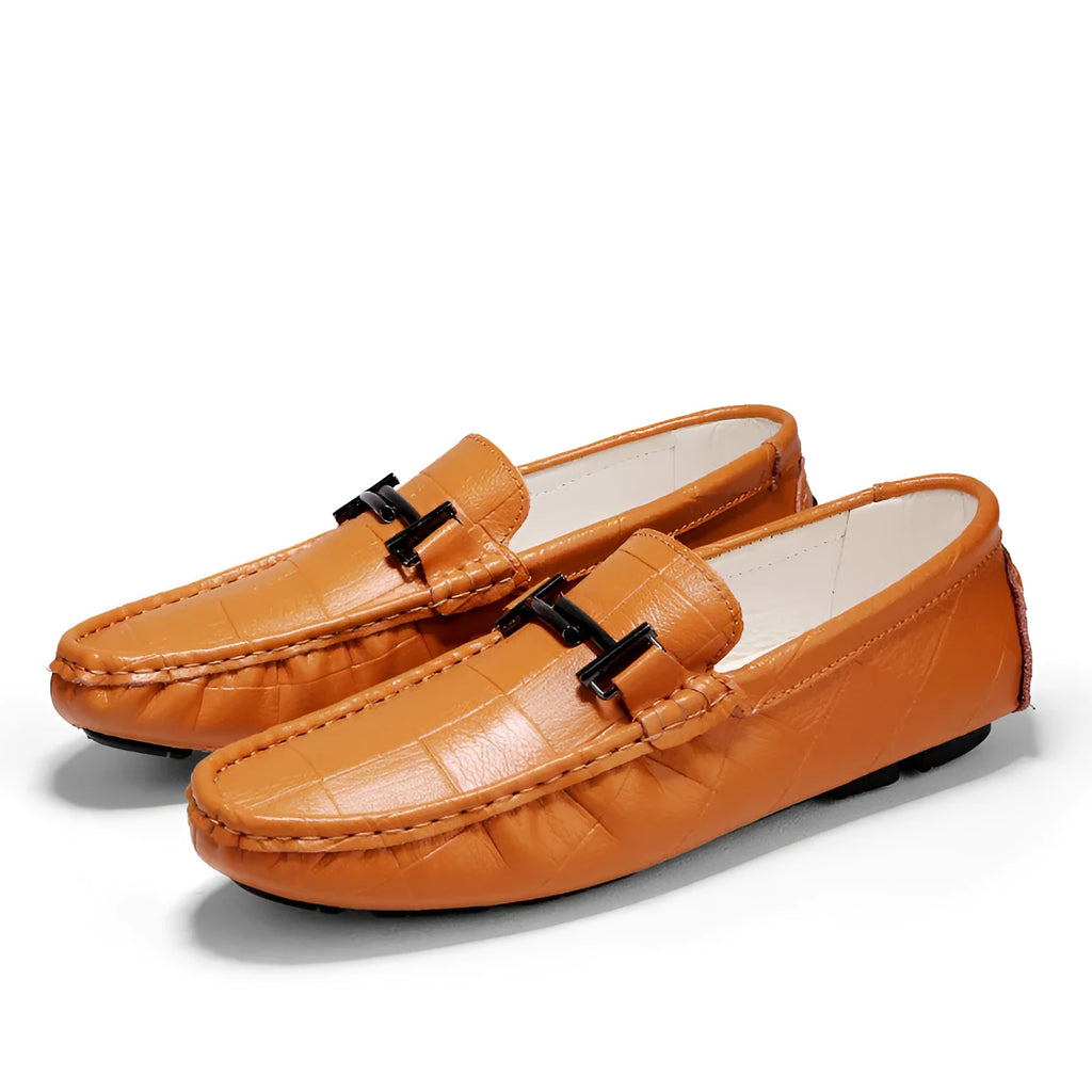 Men's brown leather slip-on loafers with a silver belt buckle detail on the front.