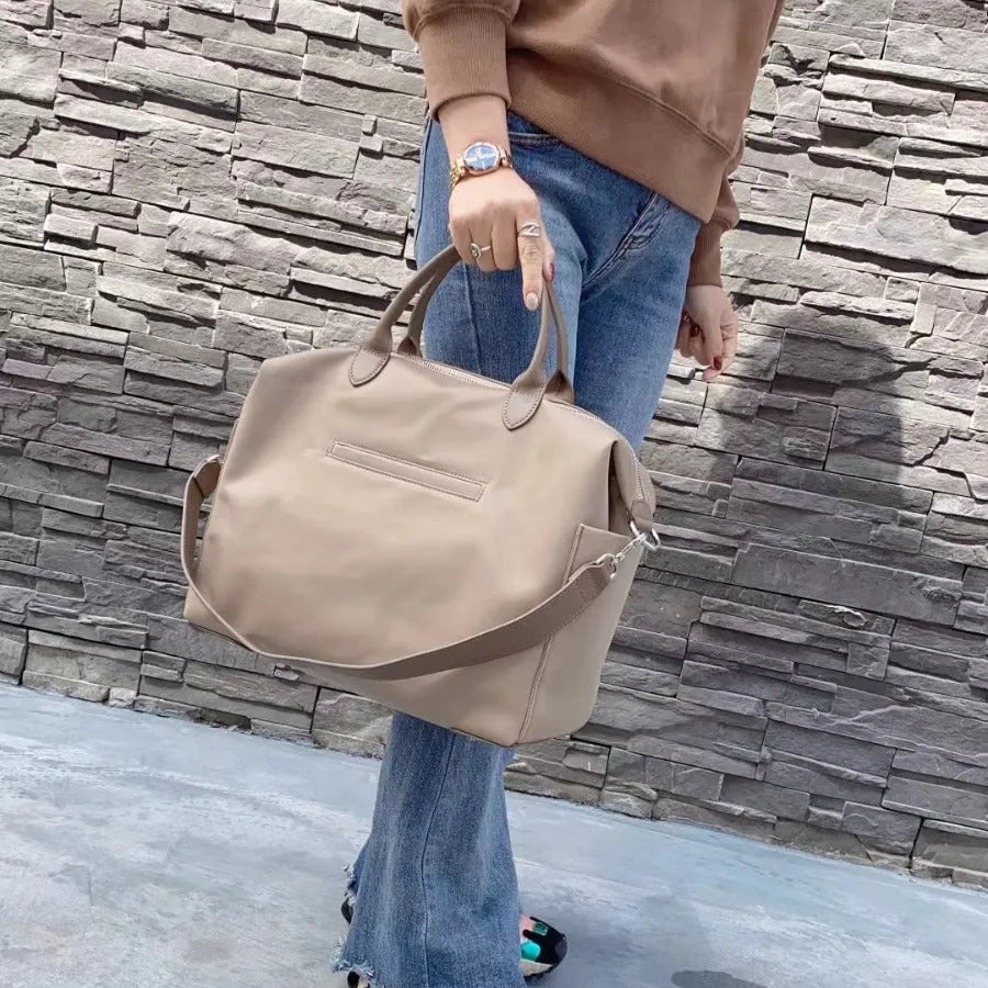 Nylon waterproof shoulder bag in black or light khaki measuring 35cm wide with leather accents