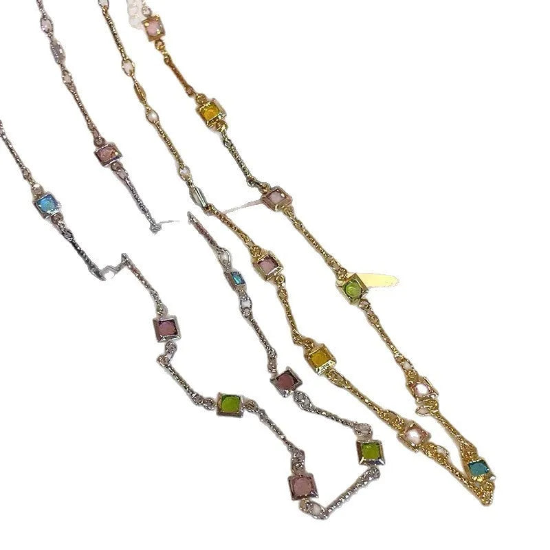Square geometric clavicle chain necklace in gold tone with artificial crystal details on a white background.