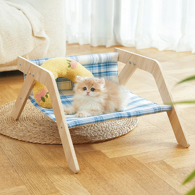 Wooden A-frame cat hammock bed with blue cloth, elevated off the floor on a carpet.