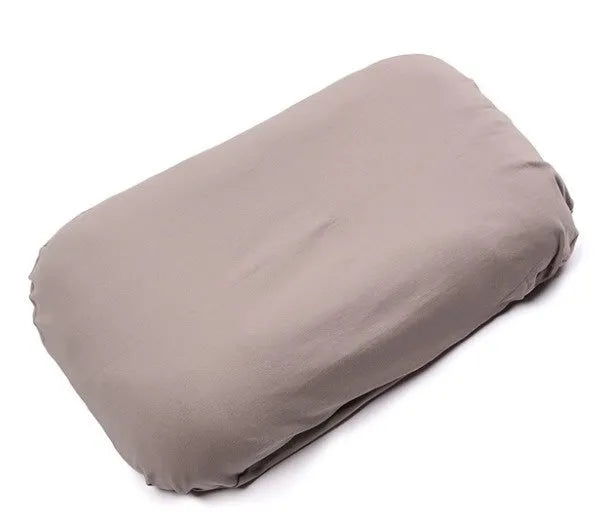 Beige portable baby nest crib cot for newborns on a neutral background.