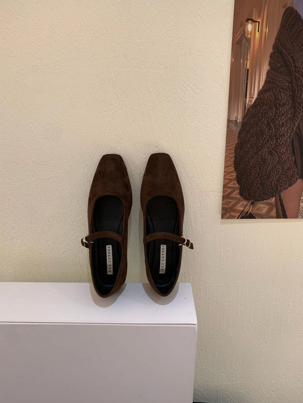 Women's black suede flat shoes with buckle closure and low heel on a neutral background