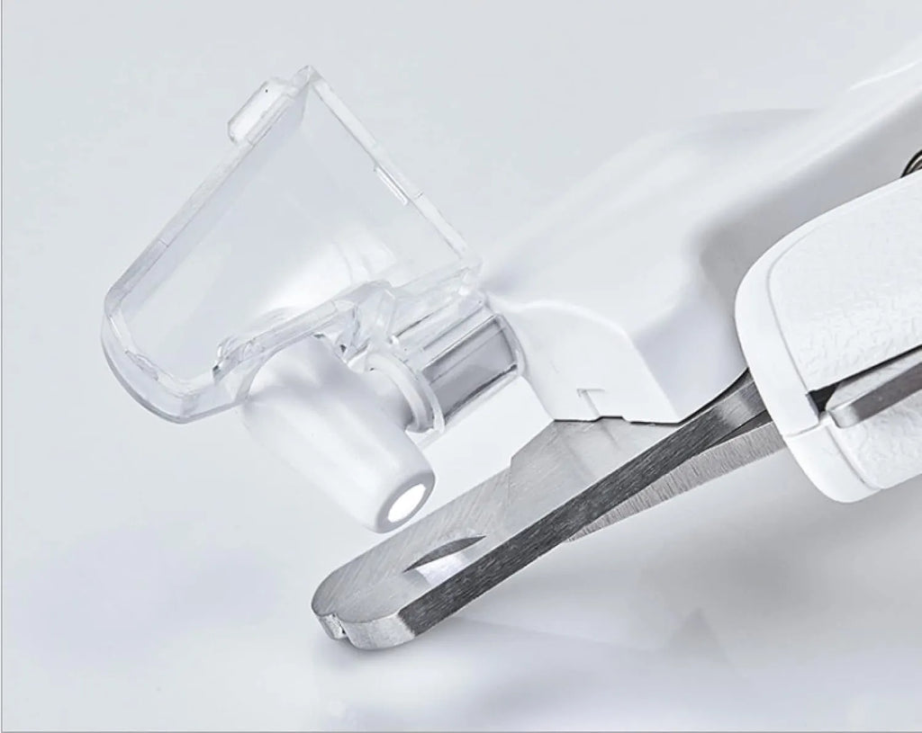 White pet nail clippers with LED light, transparent guard, and a nail file on a table