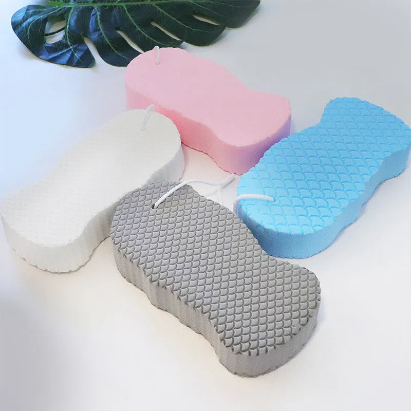 White 3D fish scale pattern bath sponge ball with hanging loop on a bathroom background.