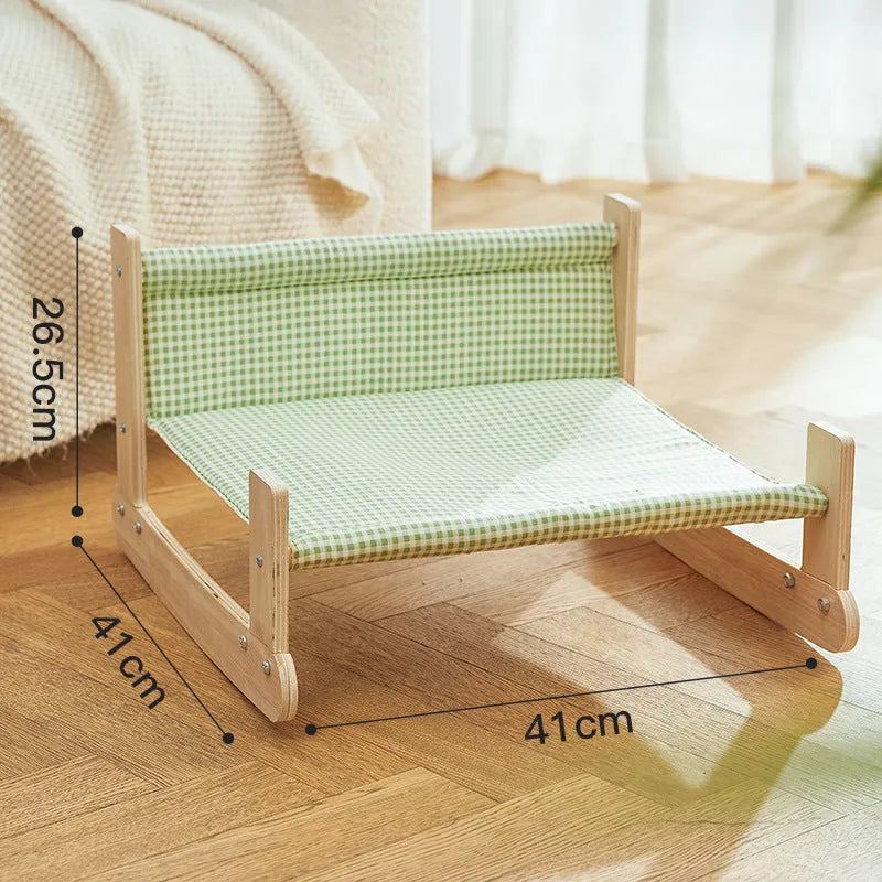 Wooden A-frame cat hammock bed with blue cloth, elevated off the floor on a carpet.