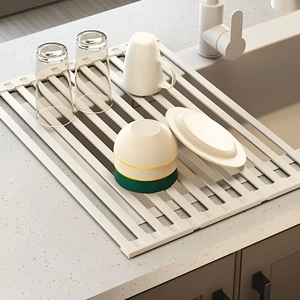 Foldable milky white stainless steel kitchen draining rack with dishes, shown next to a sink.