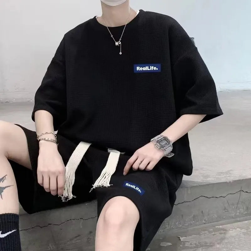 Man wearing a grey waffle-textured short sleeve leisure top and matching shorts.