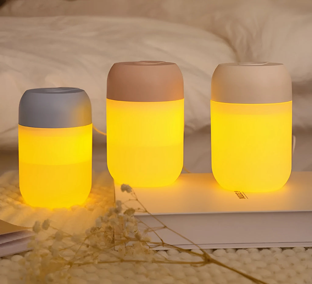 White cylindrical mini USB aromatherapy humidifier on a desk with charging cable.