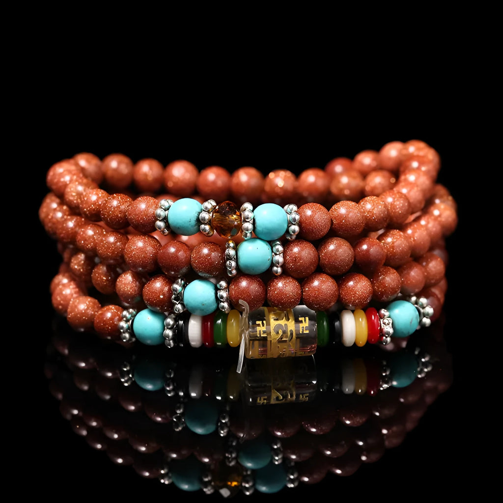 Golden star stone nugget bracelet with mantra beads and a retro fu charm on a wrist.