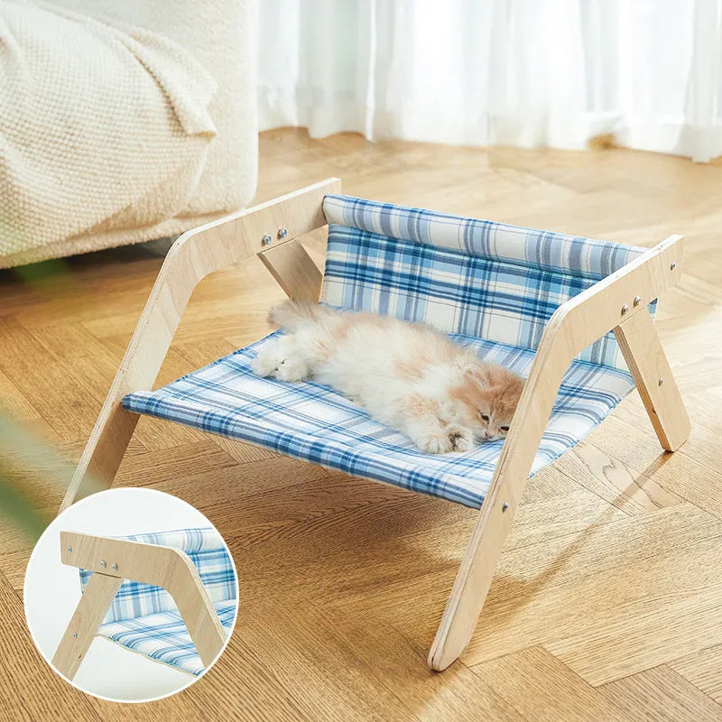 Wooden A-frame cat hammock bed with blue cloth, elevated off the floor on a carpet.