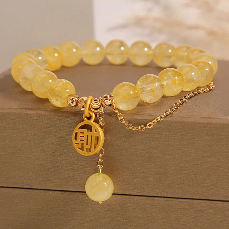 Close-up of a women's natural citrine bracelet with an electroplated Chinese character tassel.